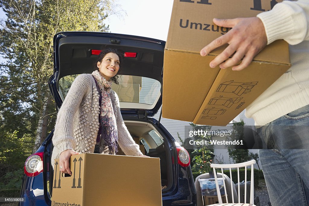 Germany, Bavaria, Grobenzell, Couple loading boxes into car, smiling