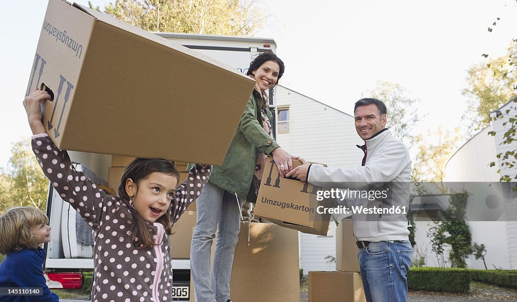 Germany, Bavaria, Grobenzell, Family with cardboard boxes for moving house, smiling