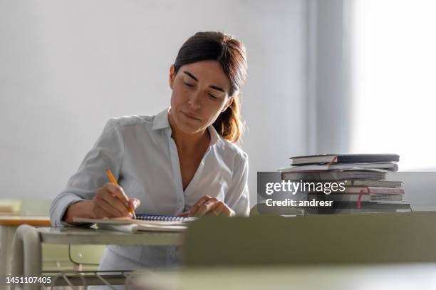 adult woman going back to school and writing in her notebook - avondschool stockfoto's en -beelden