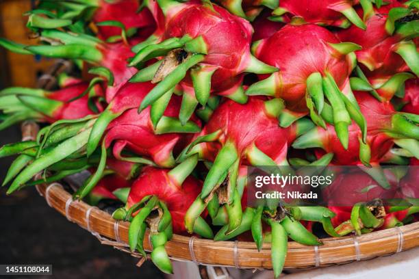 dragon fruit stacked at an outdoor market stall - dragon fruit fotografías e imágenes de stock