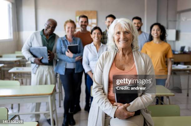 glücklicher oberlehrer im klassenzimmer mit einer gruppe von schülern - mature students stock-fotos und bilder