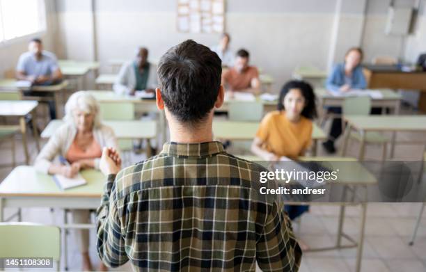 rear view of a university teacher teaching a class to a group of students - avondschool stockfoto's en -beelden