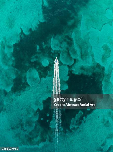 drone image looking down on a speedboat crossing an ocean lagoon, new providence, bahamas - travel photos et images de collection