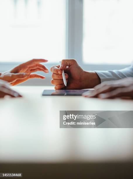 anonymous businesspeople analyzing business graph on a digital tablet - talking close up business stockfoto's en -beelden