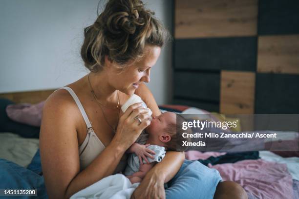 mother feeds newborn baby with bottle, at home - girls in bras photos bildbanksfoton och bilder