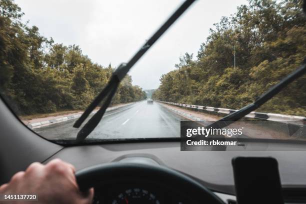 windshield wipers cleaning the windscreen in the rain - - view of the highway through the glass from inside the car - viewpoint stock pictures, royalty-free photos & images