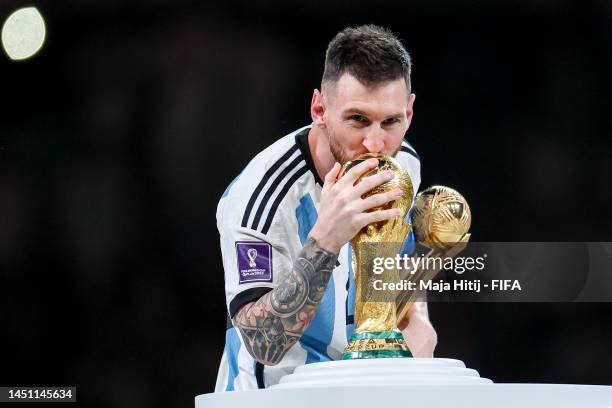 Lionel Messi of Argentina kisses the FIFA World Cup Qatar 2022 Winners' Trophy while holding the adidas Golden Boot award after the FIFA World Cup...