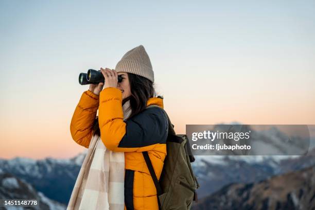 ragazza con uno zaino in montagna che guarda attraverso il binocolo - woman looking through ice foto e immagini stock