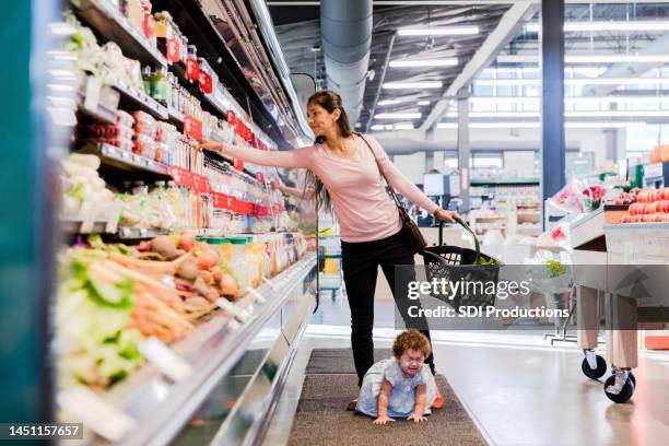 baby crawling on floor fusses as mom shops for groceries - crying baby in shop stock pictures, royalty-free photos & images