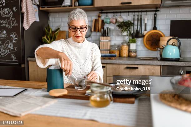 senior woman preparing a tea in her kitchen. - making tea stock pictures, royalty-free photos & images