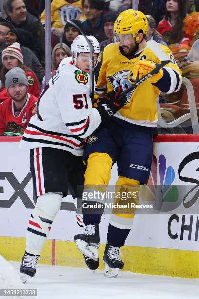 Ian Mitchell of the Chicago Blackhawks checks Roman Josi of the Nashville Predators into the boards during the first period at United Center on...