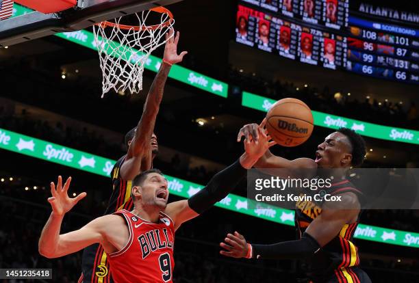 Dejounte Murray defends as Onyeka Okongwu of the Atlanta Hawks blocks a shot by Nikola Vucevic of the Chicago Bulls during the fourth quarter at...