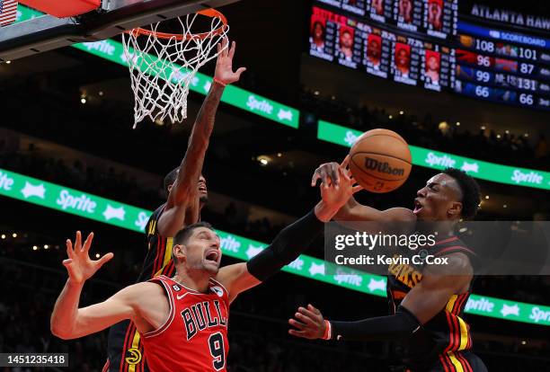 Dejounte Murray defends as Onyeka Okongwu of the Atlanta Hawks blocks a shot by Nikola Vucevic of the Chicago Bulls during the fourth quarter at...