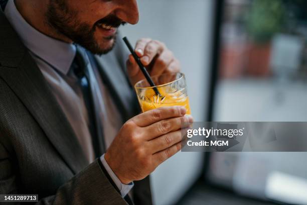 businessman drinking alcohol orange juice - cocktail corporate stockfoto's en -beelden