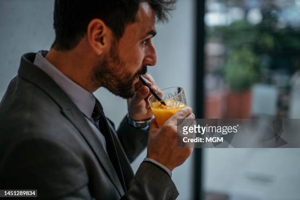 businessman drinking alcohol orange juice - cocktail corporate stockfoto's en -beelden