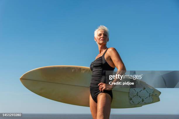 porträt der älteren frau, bereit zum surfen. - old woman in swimsuit stock-fotos und bilder