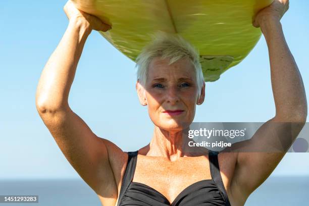 senior woman surfing. - old woman in swimsuit imagens e fotografias de stock