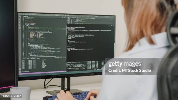 primo piano di giovani donne asiatiche sviluppatori di software che utilizzano il computer per scrivere codice seduti alla scrivania con più schermi lavorano in remoto a casa. - programmazione televisiva foto e immagini stock