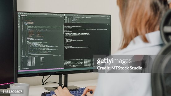 Closeup of young Asian woman software developers using computer to write code sitting at desk with multiple screens work remotely at home. Closeup of young Asian woman software developers using computer to write code sitting at desk with multiple screens work remotely at home.