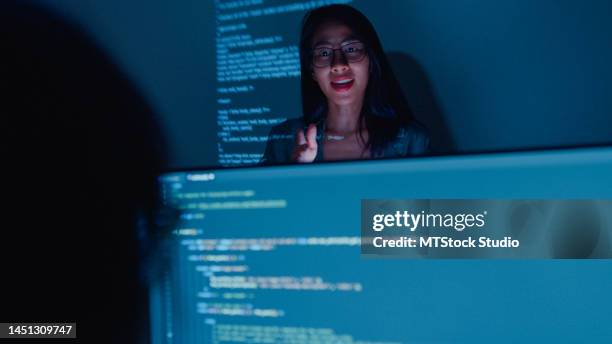 junge asiatische softwareentwicklerinnen betreuen führungskräfte, die nachts mit dem führungsteam sprechen, das den quellcode im büro analysiert. - javascript stock-fotos und bilder