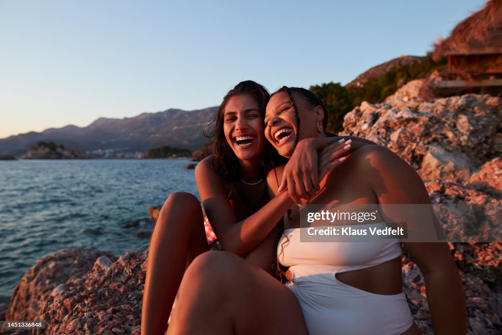 Woman enjoying sunset with friend at rocky beach
