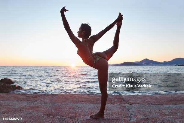 woman practicing natrajasana on pier - hot yoga stock pictures, royalty-free photos & images