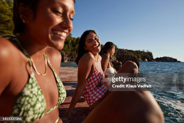 woman sitting amidst female friends on pier - red swimwear stock pictures, royalty-free photos & images