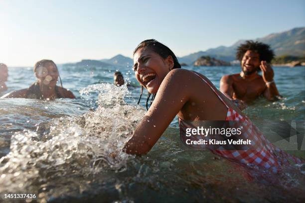 woman splashing and enjoying swim with friends - travel fotografías e imágenes de stock