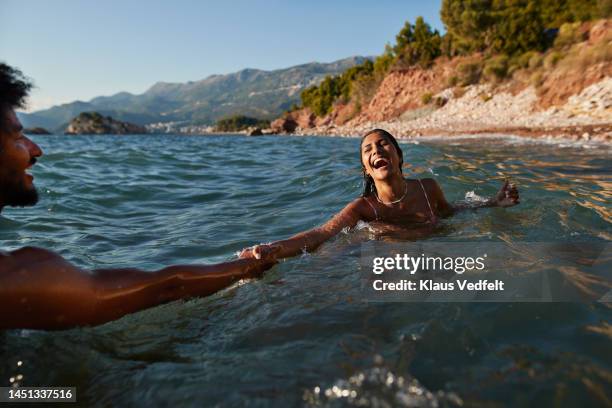 woman swimming with boyfriend in sea - love summer ストックフォトと画像