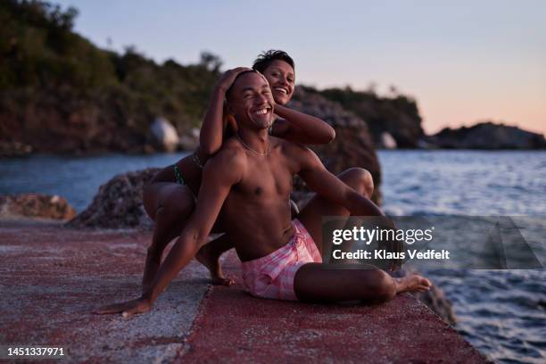 playful young couple enjoying at pier during dusk - young couple beach stock pictures, royalty-free photos & images