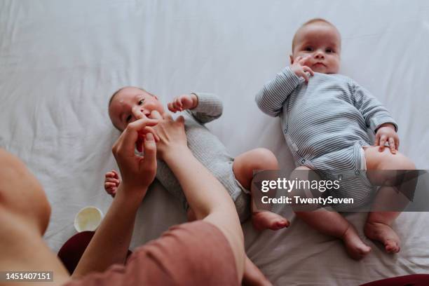 mother applying baby cream on her babies - twin males stock pictures, royalty-free photos & images