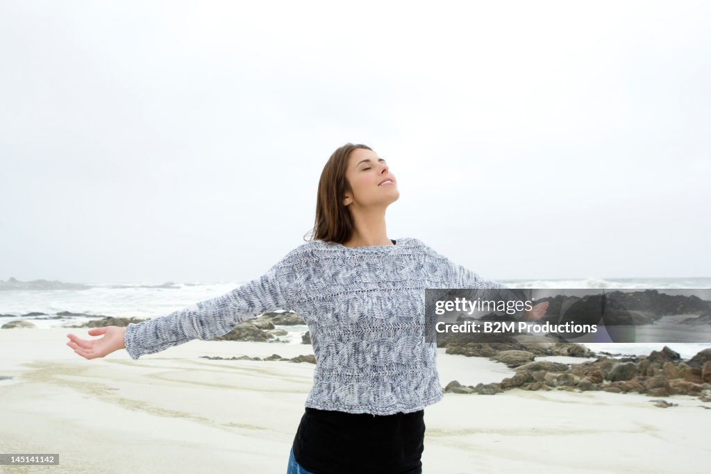 Young woman on a beach with arms outstretched