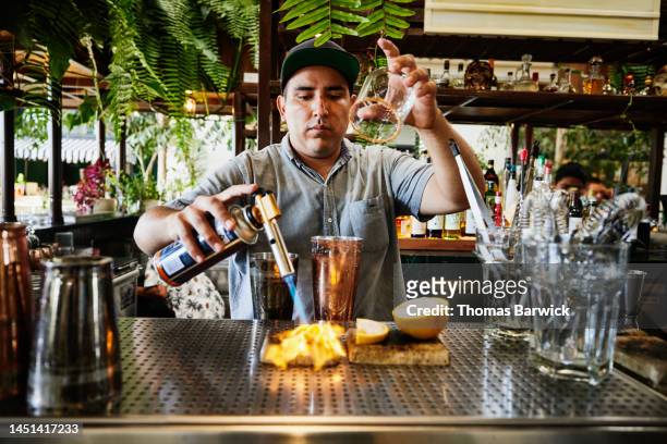 medium shot of bartender using hand torch to create craft cocktails - craft cocktail stock pictures, royalty-free photos & images