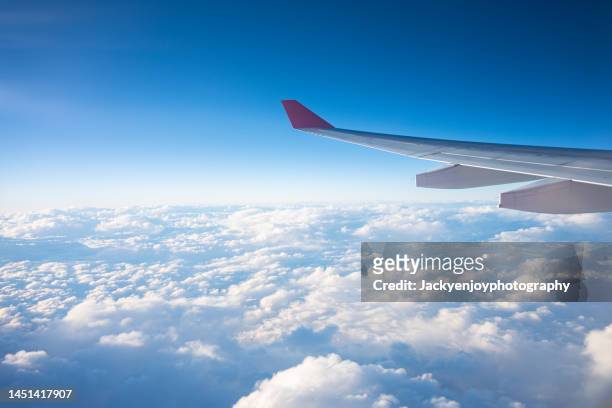 image of airplane wing flying above the clouds - commercial airplane stock pictures, royalty-free photos & images