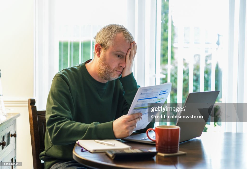 Worried man checking bills at home