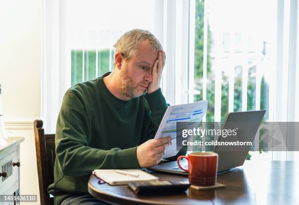 worried man checking bills at home - financial anxiety stock pictures, royalty-free photos & images