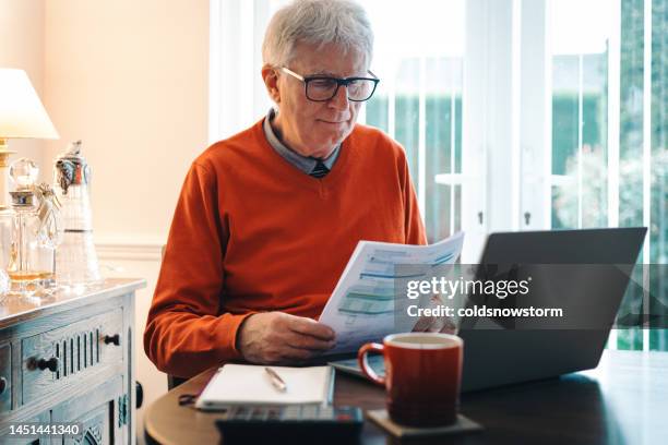 worried senior man checking bills at home - tax form stockfoto's en -beelden