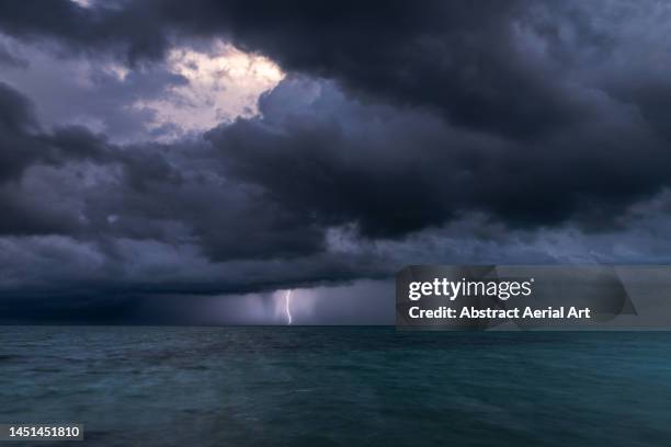 dramatic storm clouds and a lightning bolt over the ocean, nassau, new providence, bahamas - torrential rain stock pictures, royalty-free photos & images