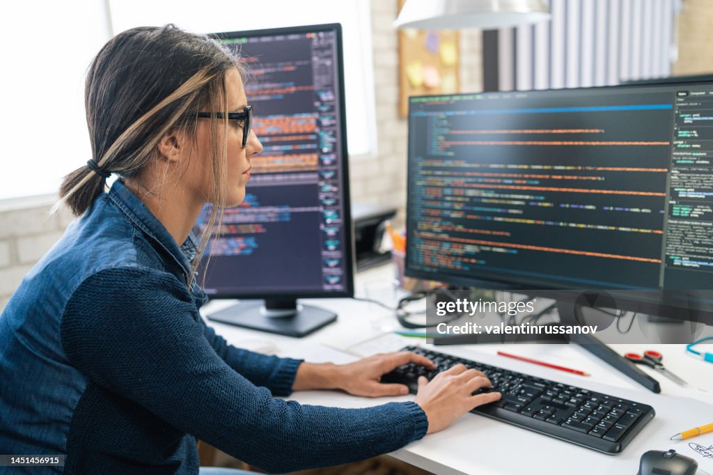 Weibliche freiberufliche Entwicklerin für Programmierung und Programmierung. Codierung auf zwei mit Bildschirmen mit Codesprache und Anwendung.