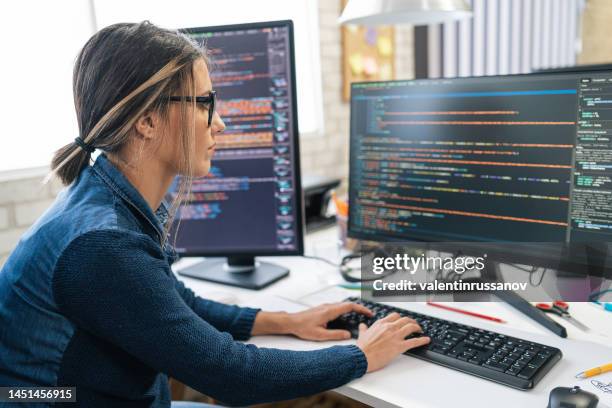 female freelance developer coding and programming. coding on two with screens with code language and application. - computersoftware stockfoto's en -beelden