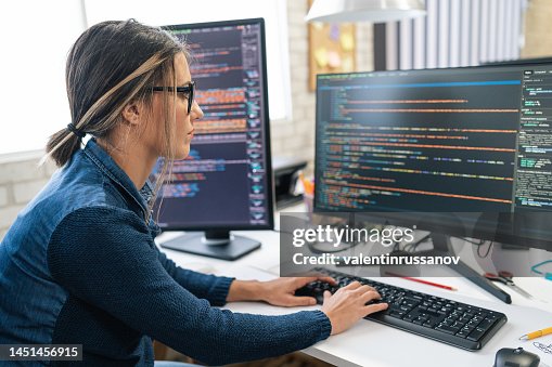 Female freelance developer coding and programming. Coding on two with screens with code language and application. Female freelance developer coding and programming. Coding on two with screens with code language and application.