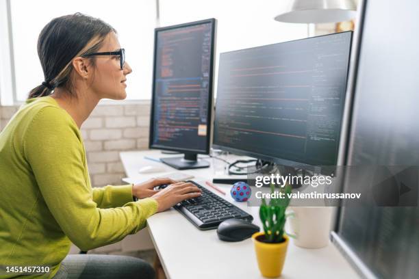 young female programmer standing on her desk, coding on the computer pc. caucasian woman checking her code app - female programmer stock pictures, royalty-free photos & images