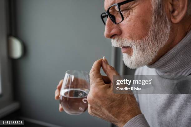 senior man taking a medical pill - acetylsalicylic acid stock pictures, royalty-free photos & images