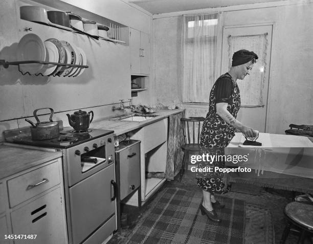 Mrs Dyett irons laundry on a table in the kitchen of her new prefabricated home at 66 Thames Street in Greenwich, south east London on 15th November...