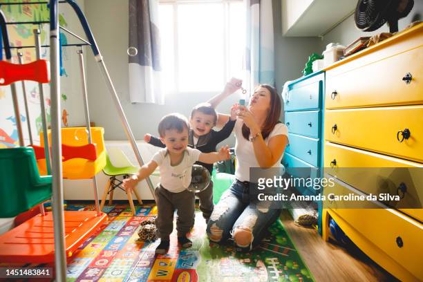 mother plays with her twin children indoors - cute twins stockfoto's en -beelden