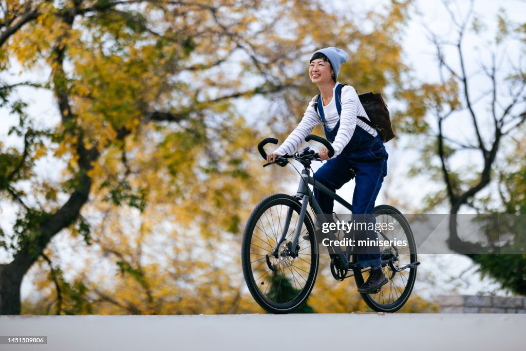 Glückliche asiatische Frau, die an einem sonnigen Tag eine Fahrradtour im Park genießt