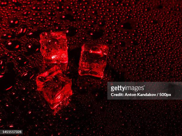 ice cubes with water drops scattered on a black background in red - hard liquor stock pictures, royalty-free photos & images