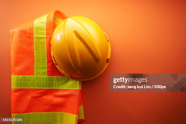 reflective waist coat and helmet against orange background,malaysia - warnweste stock-fotos und bilder