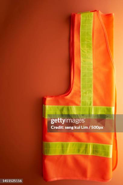 orange color reflective waist coat against orange background,malaysia - orange coat foto e immagini stock