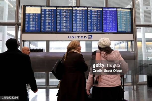 Travelers check the status of their flights at O'Hare International Airport on December 22, 2022 in Chicago, Illinois. A winter weather system...